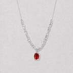 A delicate silver necklace featuring a textured, beaded chain and a central oval red agate pendant, displayed against a neutral light gray background.