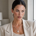 Woman wearing a beige blazer and clarity jewelry set of white agate drop earrings and necklace indoors