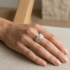 Hand wearing a textured sterling silver crystal ring with minimalist design on neutral fabric