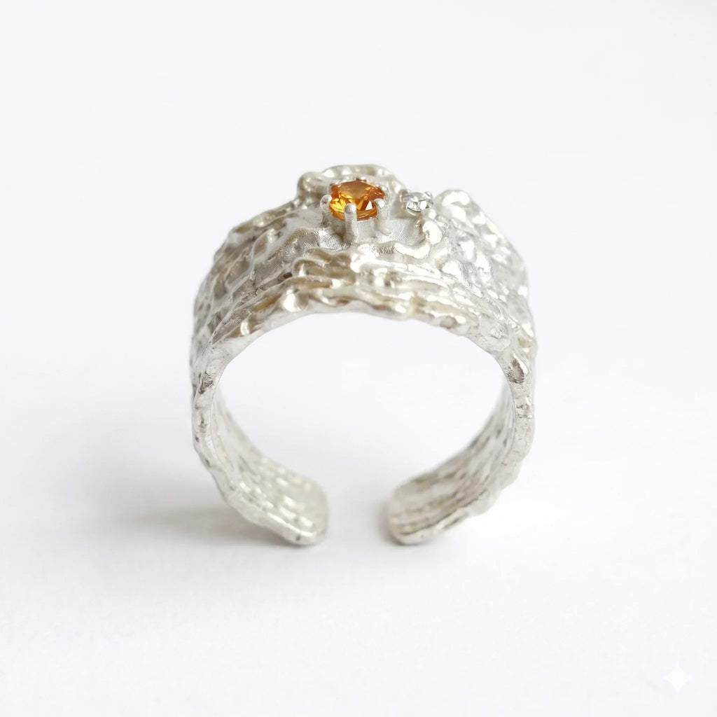 Textured sterling silver ring with orange crystal centerpiece on white background