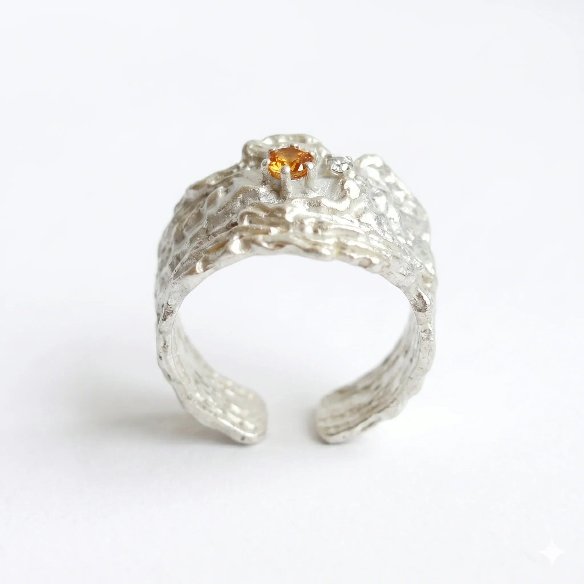 Textured sterling silver ring with orange crystal centerpiece on white background