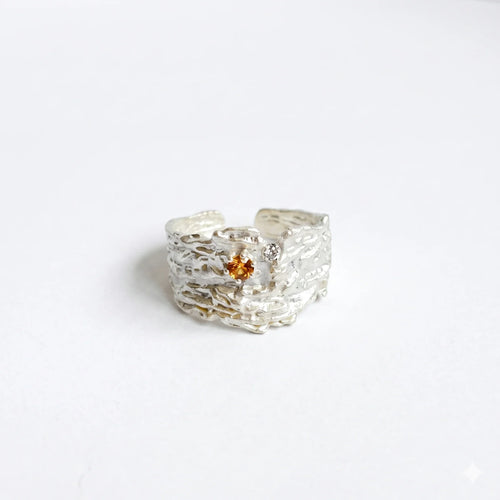 Textured sterling silver ring with orange crystal on a white background