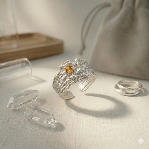 Sterling silver textured ring with yellow gemstone and clear crystals on neutral background.