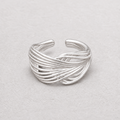 A silver-toned wrap ring with multiple twisted bands, photographed on a light textured neutral background.