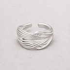 A silver-toned wrap ring with multiple twisted bands, photographed on a light textured neutral background.