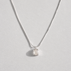 A delicate silver chain necklace with a small, bezel-set clear white agate gemstone pendant, displayed against a light gray background.