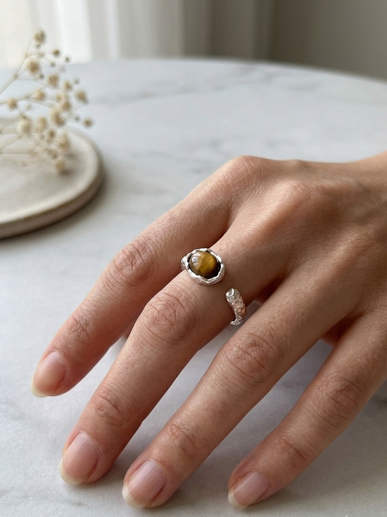 Hand wearing hammered silver ring on a marble surface with a blurred background