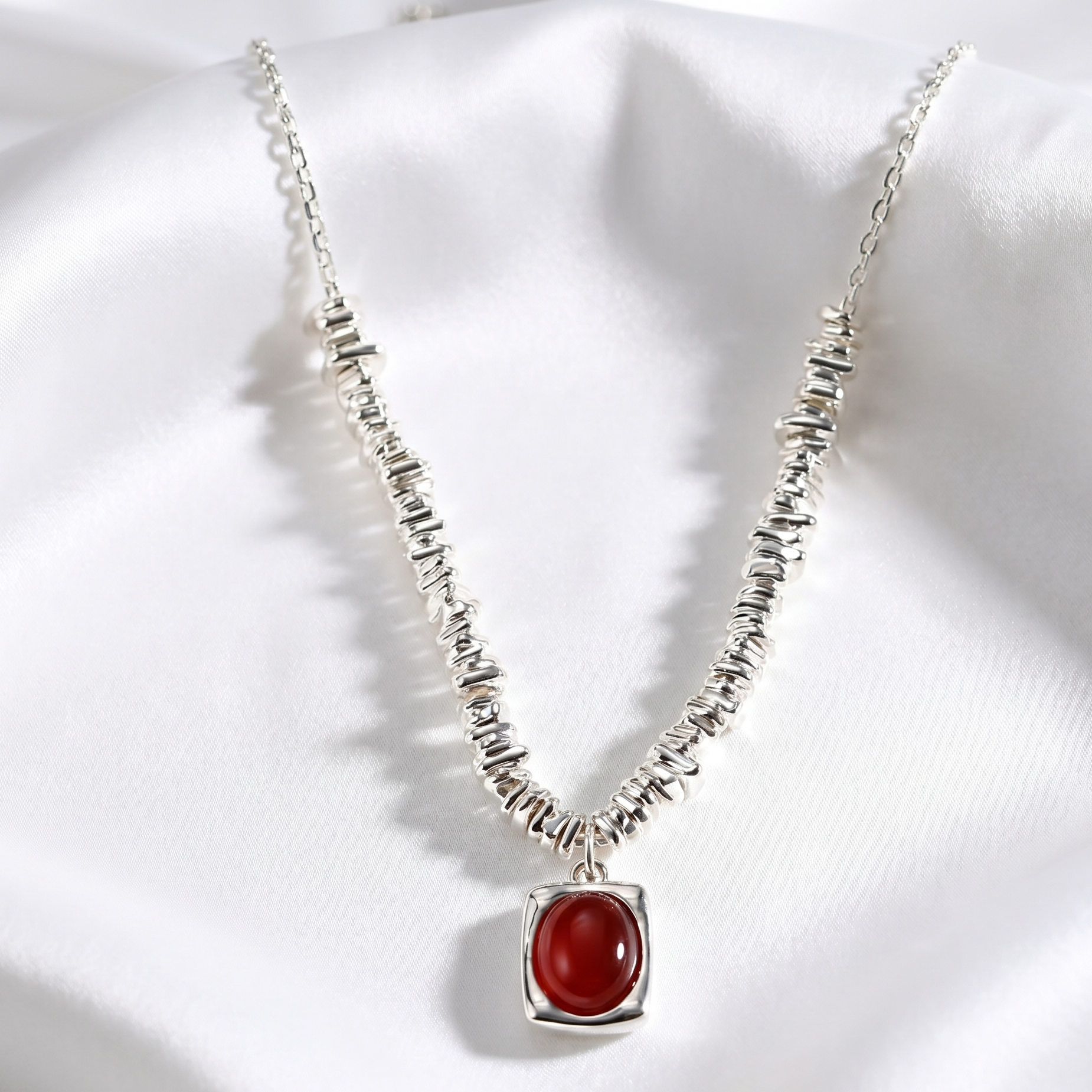 silver Necklace with a red agate pendant on a white fabric background