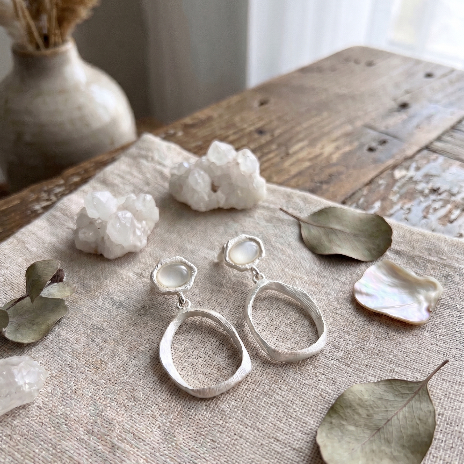 Silver earrings on a textured surface with decorative elements