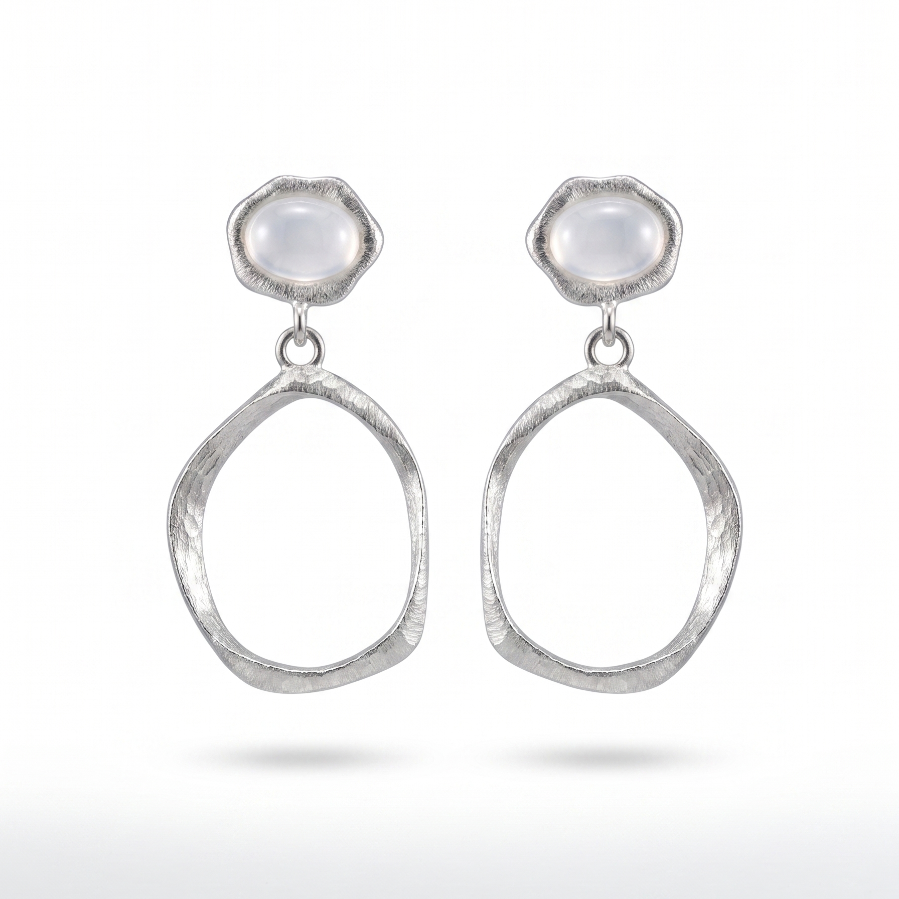 Pair of silver earrings with teardrop shapes and white agate stones on a white background