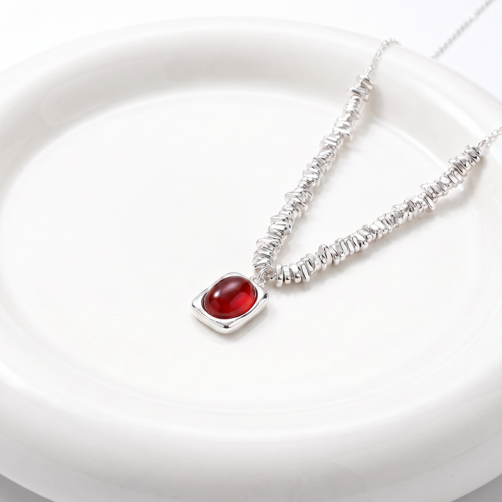 Silver necklace with a red agate stone on a white plate