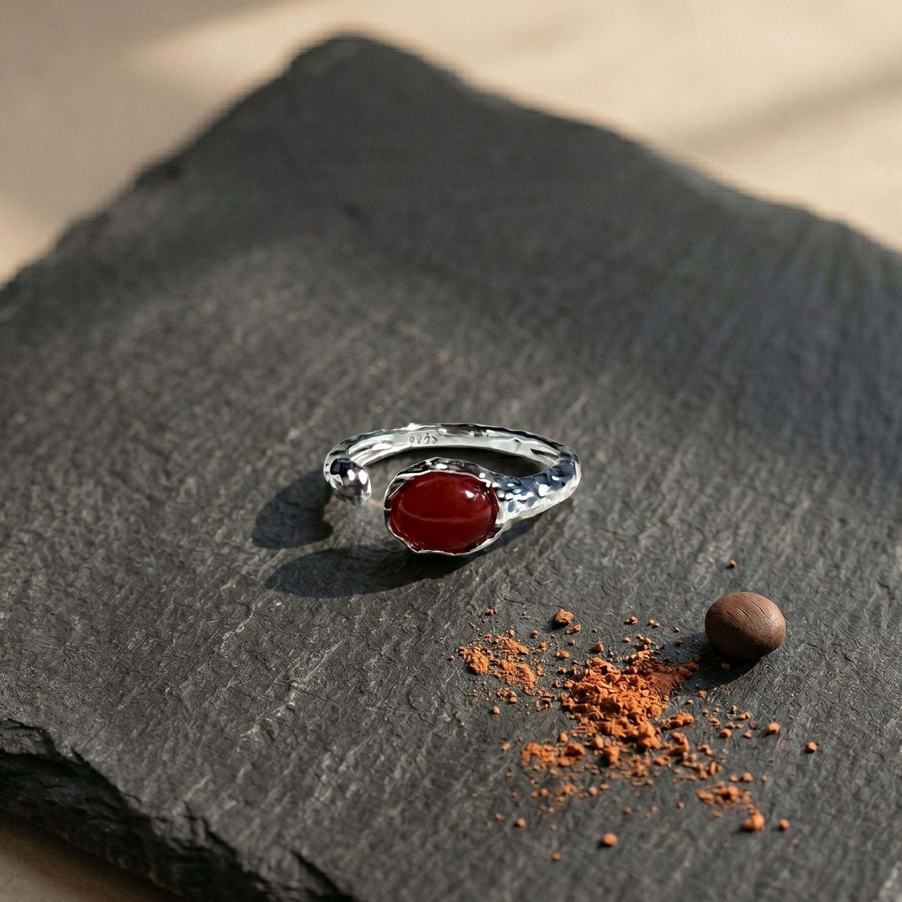 Silver ring with a red agate stone on a dark stone surface