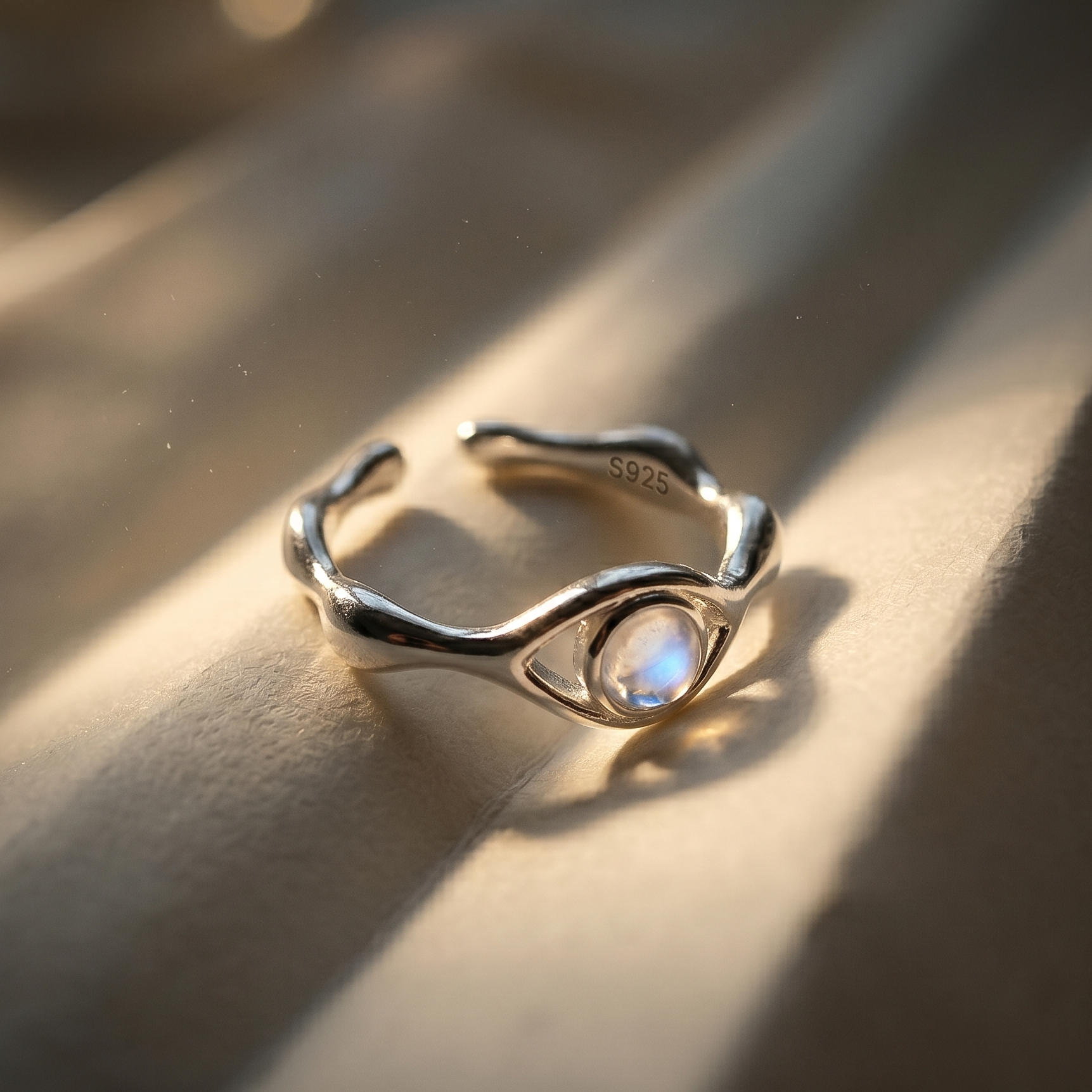 Silver ring with a moonstone on a textured surface