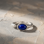 Silver ring with a blue lapis lazuli stone on a textured stone surface