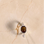 Silver ring with a brown gemstone on a beige textured surface