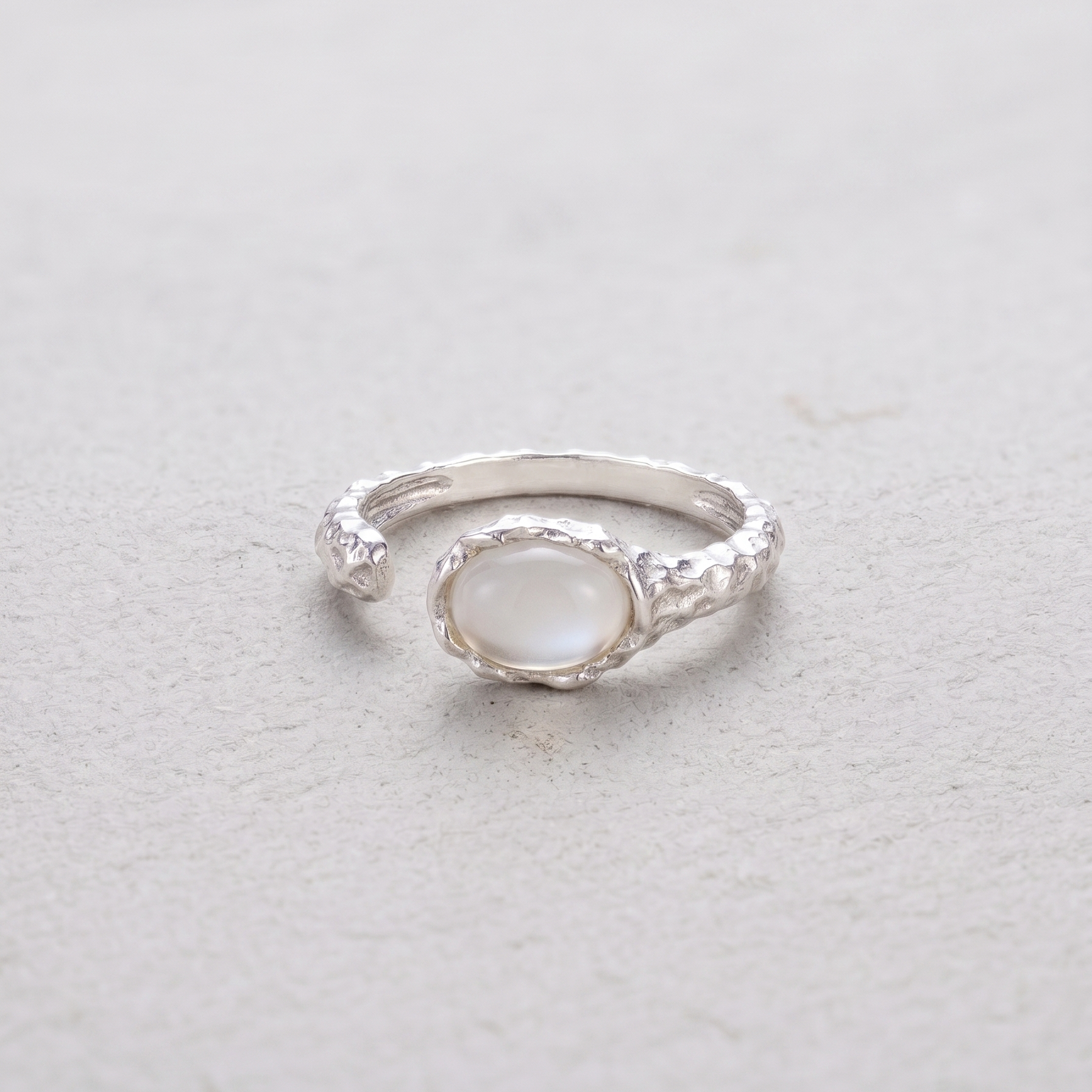 Silver ring with a white agate stone on a light gray background