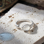 Silver ring with white agate on a textured stone surface