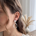 Woman wearing a silver earring with a blurred background of a vase and plants