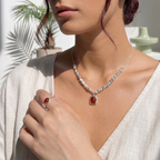 Woman wearing a jewelry set of necklace with a red agate pendant in a bright outdoor setting