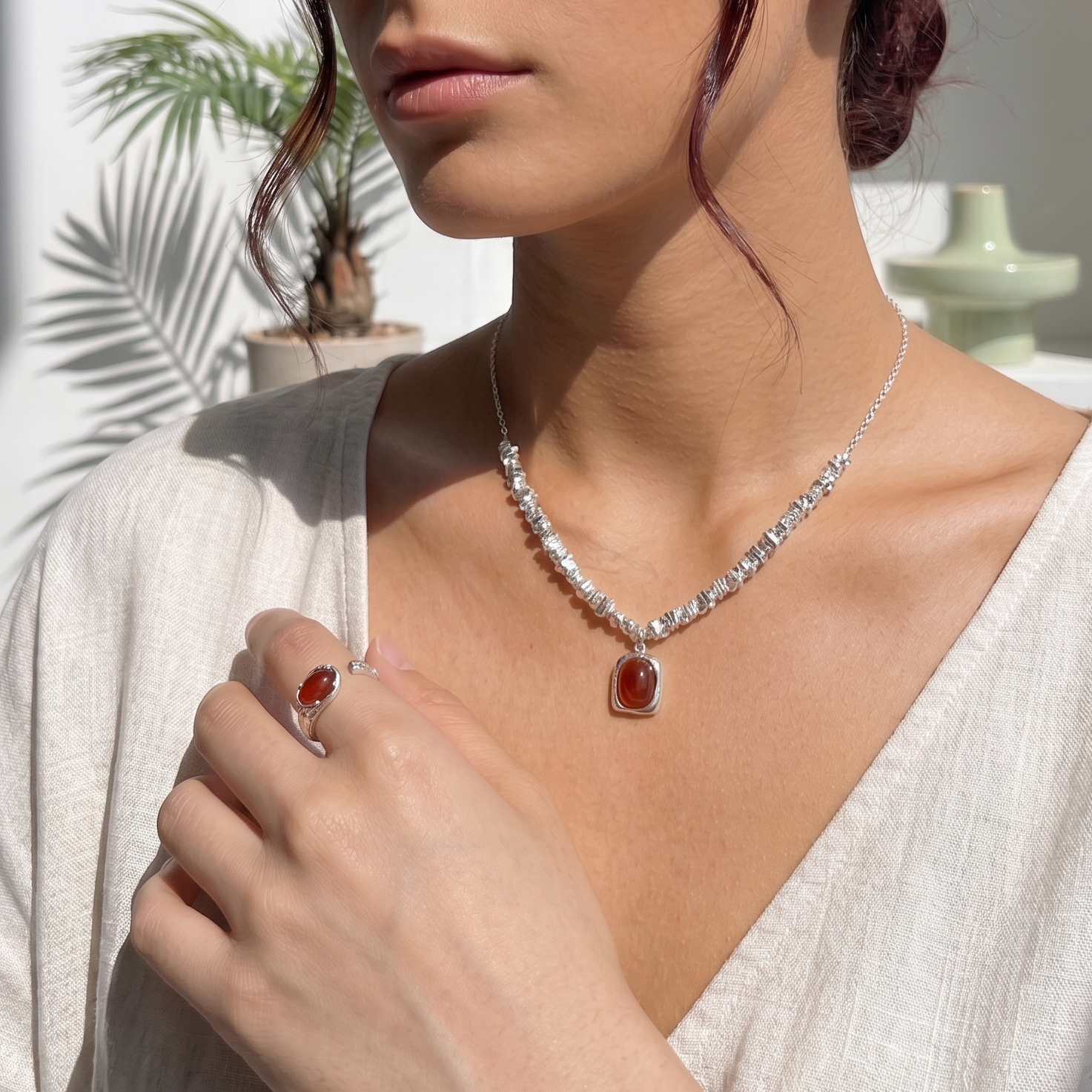Woman wearing a jewelry set of necklace with a red agate pendant in a bright outdoor setting